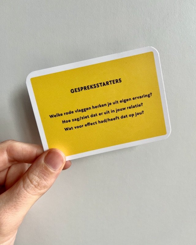 Een hand houdt het gele kaartje met gespreksstarters omhoog