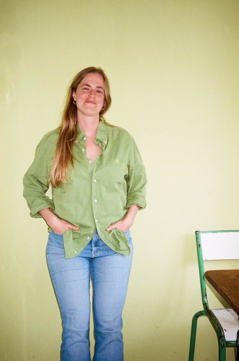 Marte van Os, lachend tegen een groene muur